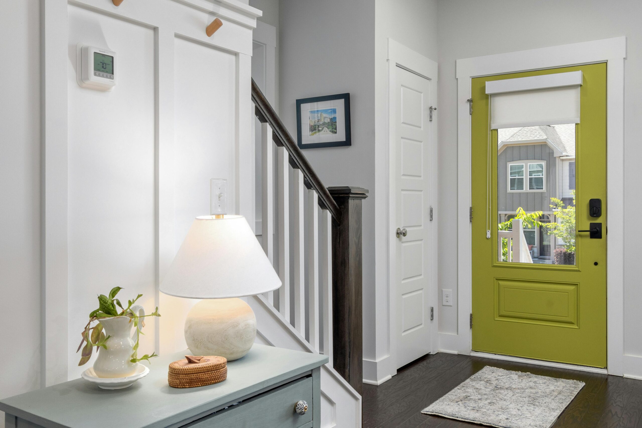 A well-lit modern entrance featuring a green door and stylish interior design elements.